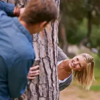 Couple peeking aroud tree